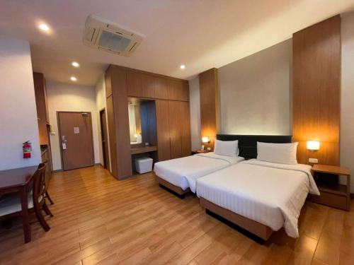 a hotel room with two beds and a desk at Sriracha Orchid Hotel in Si Racha