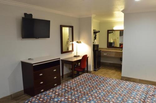 a hotel room with a bedroom with a bed and a desk at Welcome Inn Corona in Corona