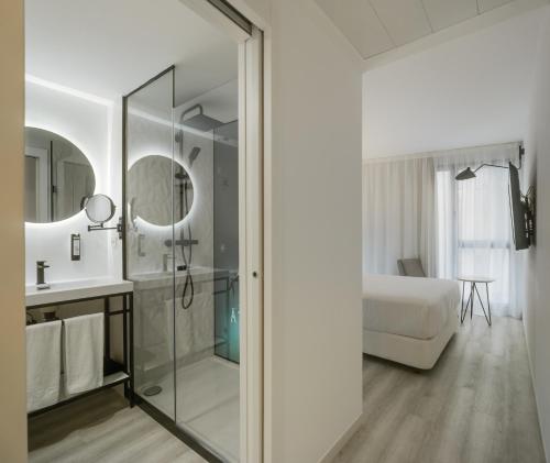 a bathroom with a glass shower and a bedroom at Dormirdcine Alicante in Alicante