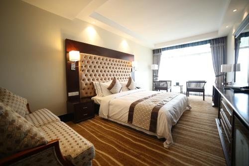 マータレーにあるThe Grand Mountain Hotelの大きなベッドと椅子が備わるホテルルームです。