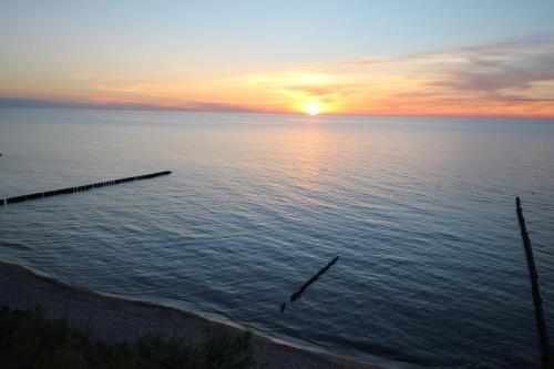 a sunset over a body of water with a pier at Apartamenty Na Klifie in Ustronie Morskie