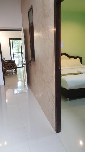 pokój z drzwiami otwierającymi się na sypialnię z łóżkiem w obiekcie Raina-Suanpa Lung Sood Farmstay w mieście Suphanburi