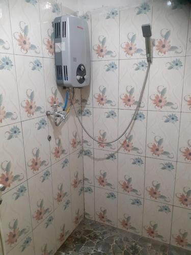 a bathroom with a heater on a tiled wall with flowers at Ijen Miner Family Homestay in Banyuwangi