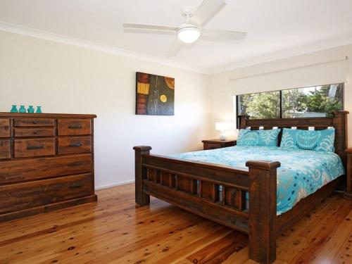 a bedroom with a bed and a dresser and a window at The Lobster Pot in Currarong