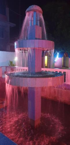 a fountain with a waterfall in a park at night at London House Resort in Birātnagar