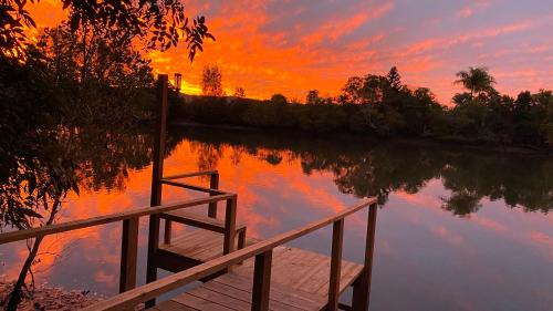 a sunset over a body of water with a wooden dock at Bli Bli House Riverside Retreat in Twin Waters