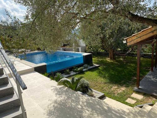 einen Pool in einem Garten mit Bäumen und Gras in der Unterkunft Vila Ivka Gardens in Klek
