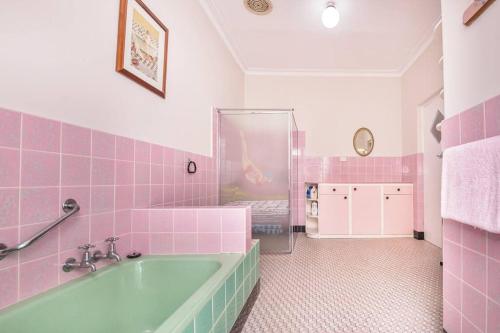 uma casa de banho cor-de-rosa com uma banheira e azulejos cor-de-rosa em River Views in the Heart of Town em Northam