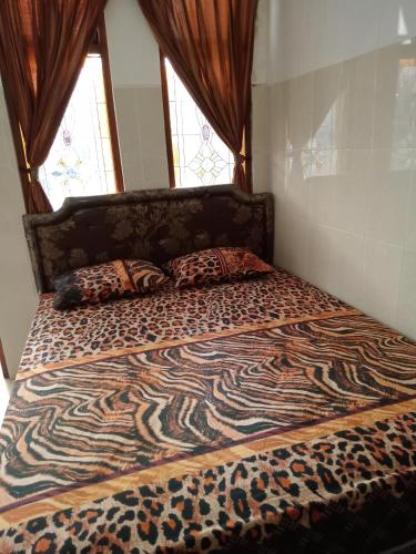 uma cama com um edredão de estampa de zebra e 2 almofadas em Cempaka 2 Homestay em Legian