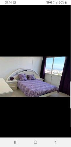 - une chambre avec un lit doté de draps violets et une fenêtre dans l'établissement Appartement Laurent Bonnevay, à Villeurbanne