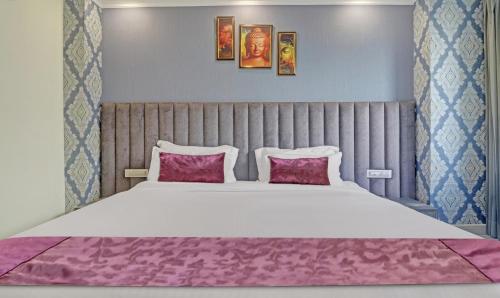 a bedroom with a large bed with two pink pillows at Hotel Woodville Inn - Hotel in Mcleodganj in McLeod Ganj