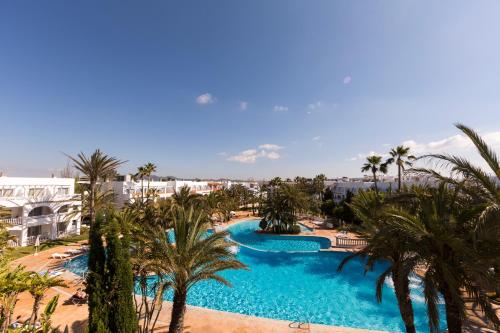 an aerial view of a resort pool with palm trees at Hotel Calimera Fido Gardens in Cala d´Or