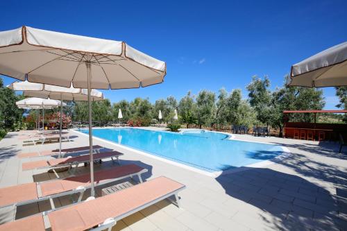 a swimming pool with chairs and umbrellas at Agriturismo Posta Pastorella in Vieste