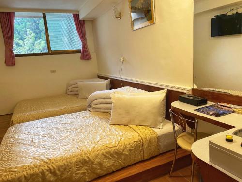 um quarto com 2 camas e uma secretária com uma secretária. em 登山別館 em Distrito de Zhongzheng