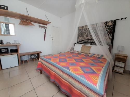 a bedroom with a bed with a mosquito net at Villa Osumare Guest House in Flic-en-Flac