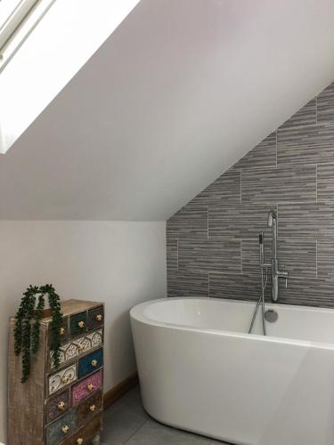 a white bath tub in a room with a attic at The Manor Barn in Northampton