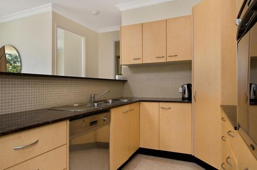 a kitchen with wooden cabinets and a sink at Santorini Twin Waters in Mudjimba