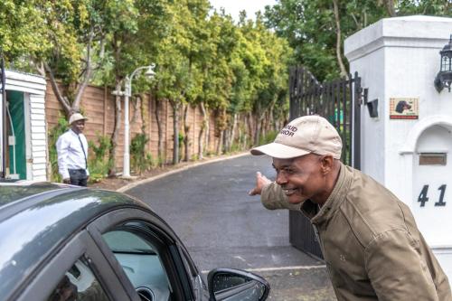an older man pointing at a car on a street at Anoud Manor in Hout Bay