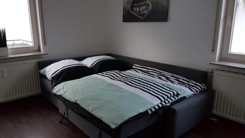 a small bed in a room with two windows at Ferien- und Businessapartment I Modern mit WLAN und Parkplatz nahe Zentrum, Automobil- und Tech-Firmen, Messe in Renningen