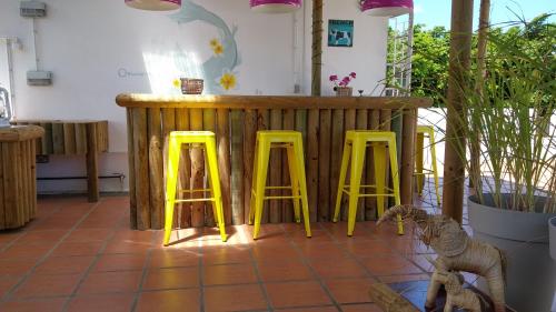 a counter with three yellow stools in a room at Villa Osumare Guest House in Flic-en-Flac