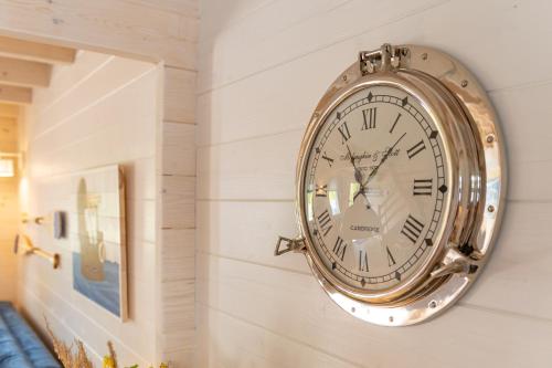 a clock hanging on a wall next to a mirror at Domki nad morzem Otulone Słońcem in Rowy