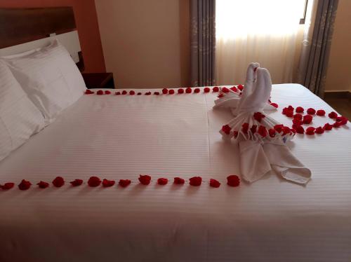 a white bed with red rose petals on it at KILIMANI BREEZE HOTEL in Wote