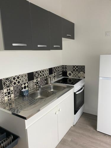 La cuisine blanche est équipée d'un évier et d'un réfrigérateur. dans l'établissement Vivez l'Echappée mer - 4 chemins - St Vincent - Plage, au Havre