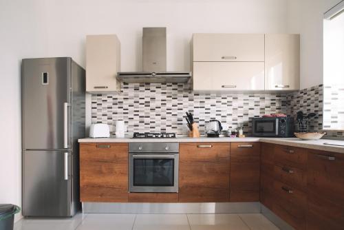 a kitchen with wooden cabinets and a stainless steel refrigerator at Modern 3 bedroom with AC apartment in Żabbar