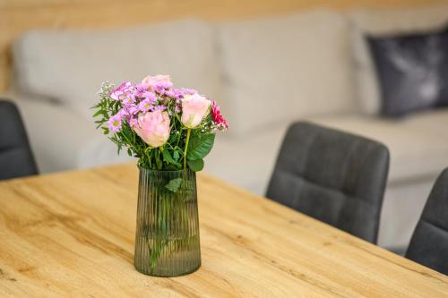 a vase filled with pink flowers sitting on a table at Apartmány 629 in Harrachov