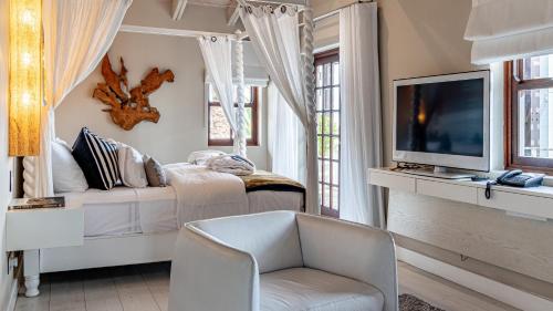 a white living room with a tv and a chair at The Glen Boutique Hotel & Spa in Cape Town