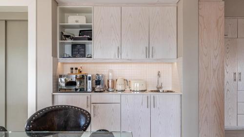 a kitchen with white cabinets and a chair in it at The Glen Boutique Hotel & Spa in Cape Town