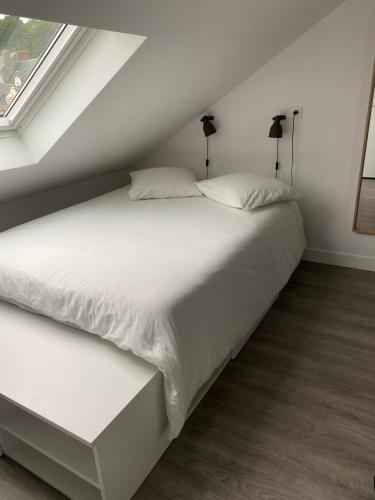 un lit avec des draps blancs et des oreillers dans une chambre dans l'établissement Vivez l'Echappée mer - 4 chemins - St Vincent - Plage, au Havre
