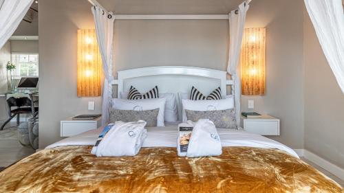 a bedroom with a large white bed with two pillows at The Glen Boutique Hotel & Spa in Cape Town