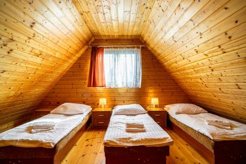 two beds in a wooden room with a window at Ośrodek Wypoczynkowy KLIF in Gąski