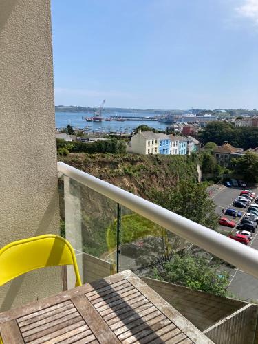 a balcony with a yellow chair and a view of a parking lot at Ocean Breeze No 5, Seaview & Parking in Falmouth