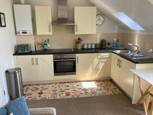 a small kitchen with white cabinets and a sink at 5 Porth Gwel in Falmouth