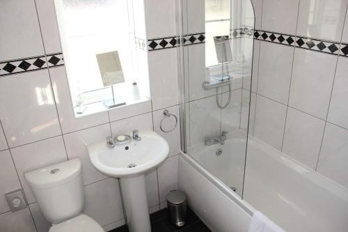 a white bathroom with a sink and a toilet and a tub at Ocean Breeze No 5, Seaview & Parking in Falmouth