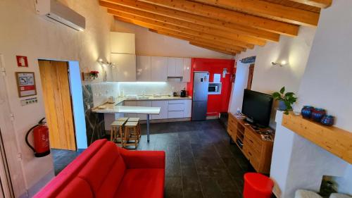 a living room with a red couch and a kitchen at Charme de Monsaraz in Monsaraz