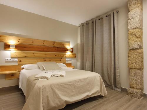a bedroom with a large white bed with a wooden wall at Apartamentos Ria de Aldan in Aldán