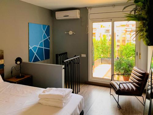 ein Schlafzimmer mit einem Bett, einem Stuhl und einem Fenster in der Unterkunft Incredible 2BR Penthouse with Urban Rooftop Garden in Barcelona