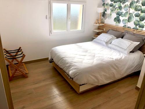 une chambre avec un lit avec des draps blancs et une fenêtre dans l'établissement La Parenthèse Balnéo T2 Cosy de 40m² avec terrasse, à Ternay