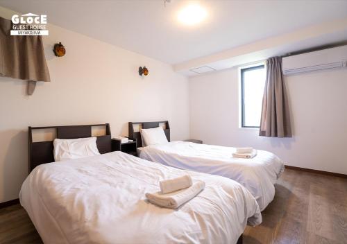 two beds sitting next to each other in a bedroom at 石田ヴィレッジ 満天の星空が見えるログハウスを貸し切り 宮古空港から8分 無料駐車場付 長期滞在可 in Miyako Island