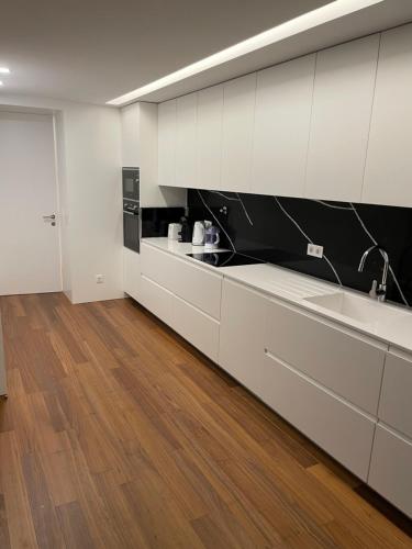 a kitchen with white cabinets and a wooden floor at Orpheu Deluxe Apt - Parque das Nações in Lisbon
