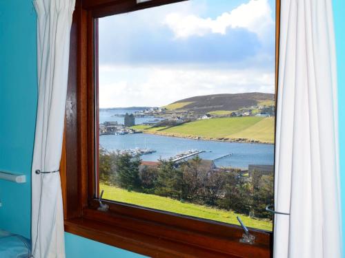 a window with a view of a body of water at Easterhoull Chalets in Scalloway