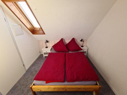 een bed met rode kussens in een kleine kamer bij Ferienwohnung-Rotmoosblick-direkt-am-Rande-unberuehrter-Natur in Isny im Allgäu