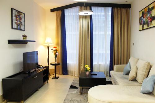 a living room with a couch and a tv at Al Diar Sawa Hotel Apartments in Abu Dhabi