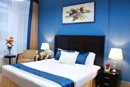 a bedroom with a bed and a blue wall at Al Diar Sawa Hotel Apartments in Abu Dhabi