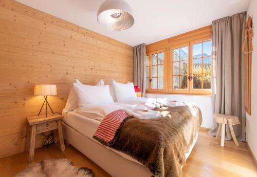 a bedroom with a bed with a wooden wall at Les Residences Waldbort in Wengen