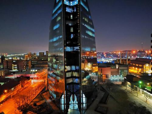 a tall glass building in a city at night at 1007-Stunning Studio apt with incredible Joburg views in Johannesburg