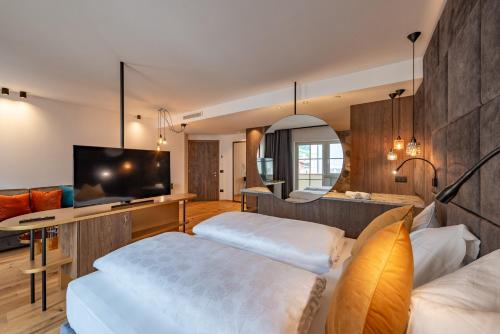 a hotel room with two beds and a flat screen tv at Hotel Goldene Traube in Termeno